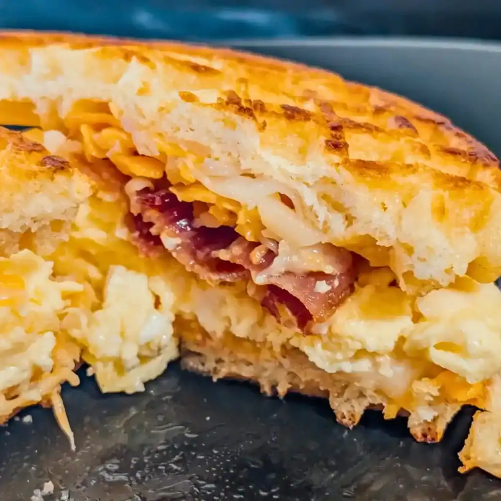 featured image of waffle grilled cheese sandwich with bacon and egg on dark plate