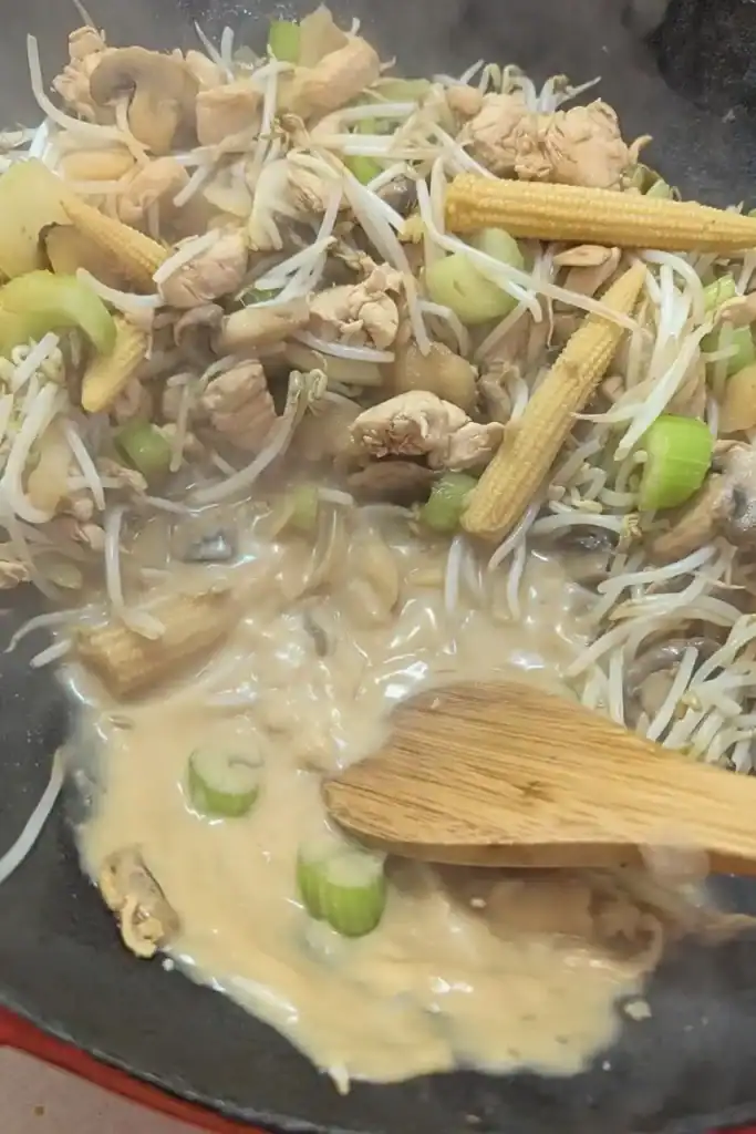 adding the cornstarch slurry to the juices in the wok for chicken chop suey