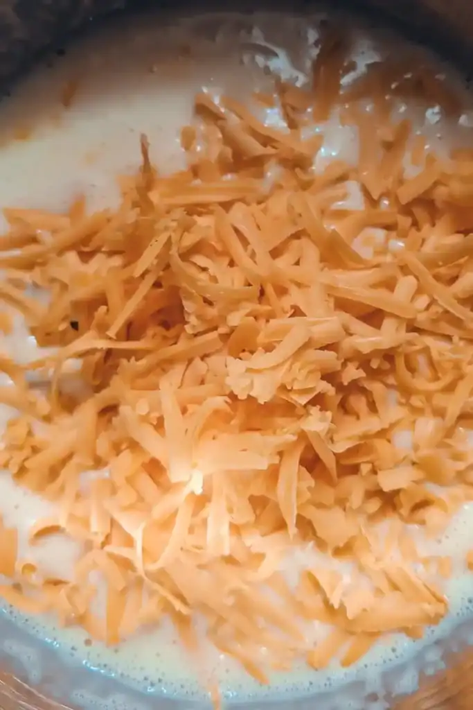 adding shredded cheddar cheese to the egg mixture