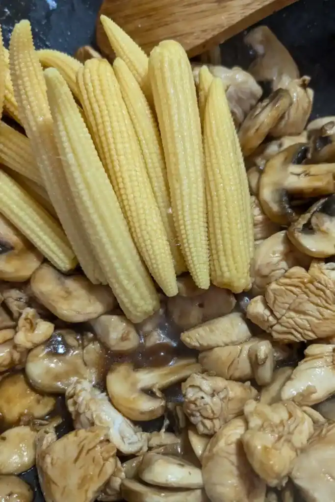 adding canned baby corn that's been drained to the wok
