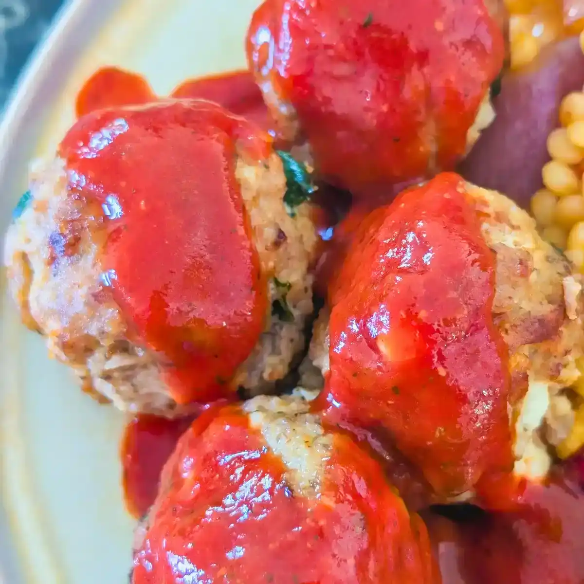 top down view of turkey meatballs with harissa sauce on beige plate edge showing