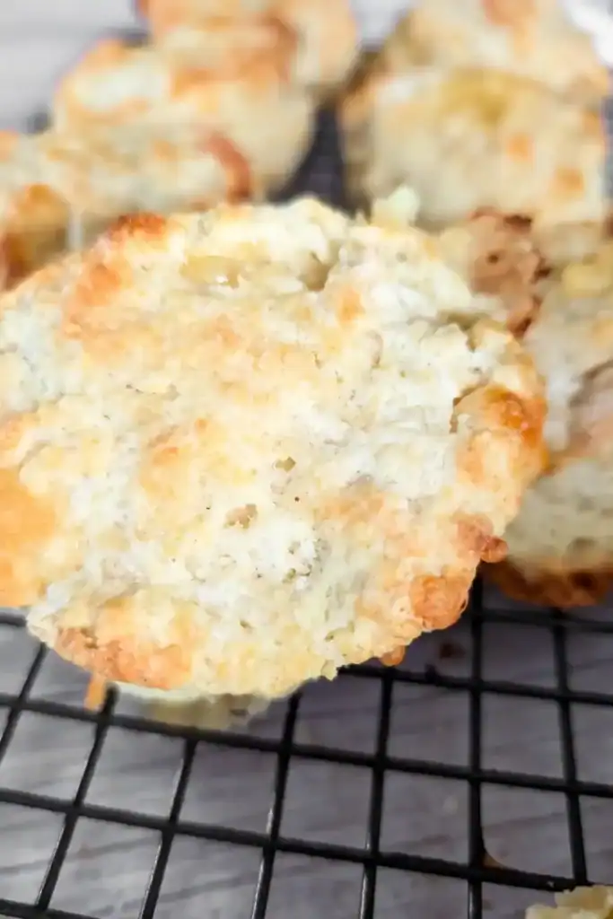 closeup top of a cheese biscuit with others in the background on wire baking rack