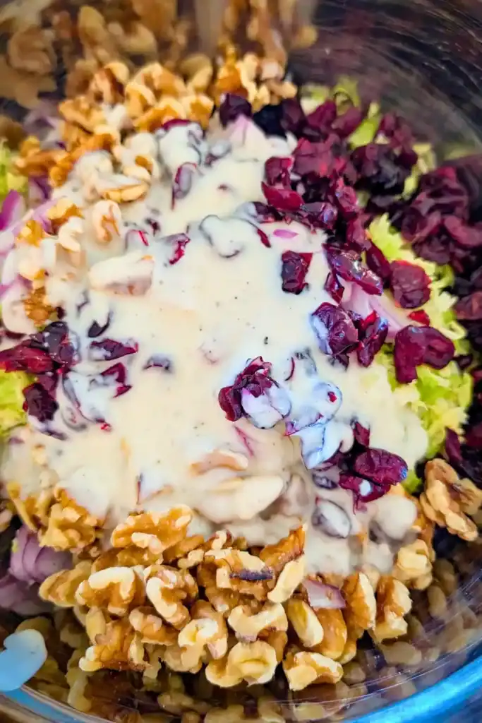adding salad dressing to the raw brussels sprouts salad