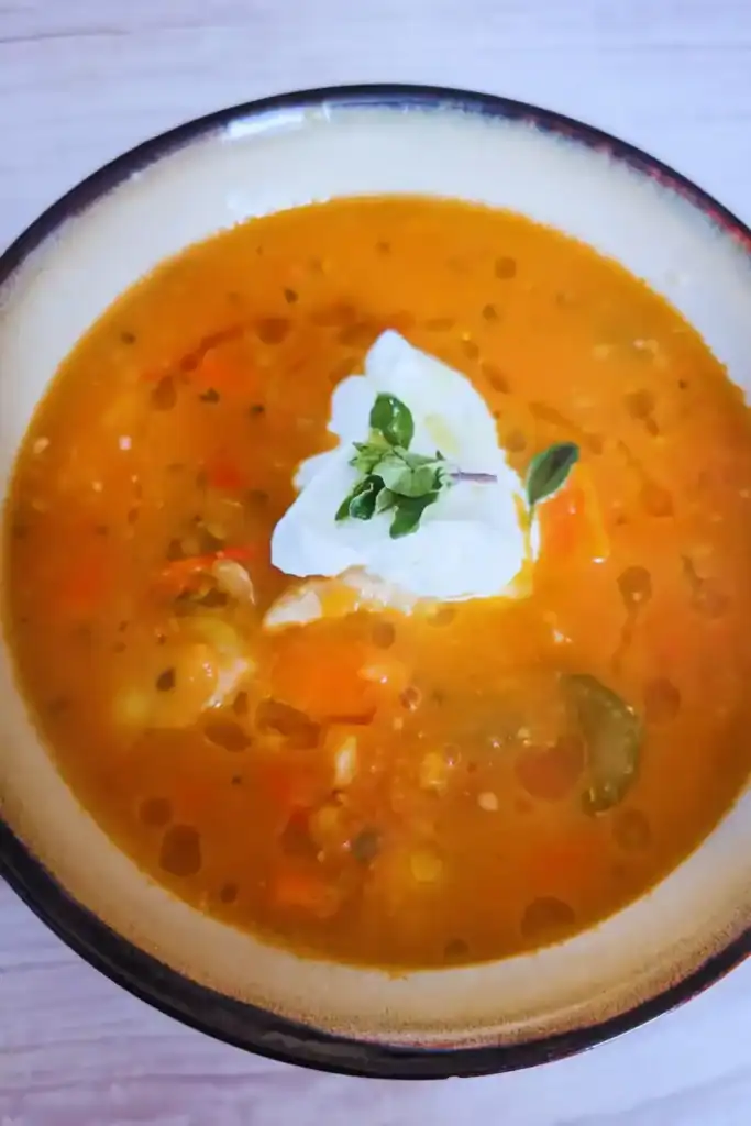 adding garnish and truffle oil to the roasted tomato chicken and vegetable soup