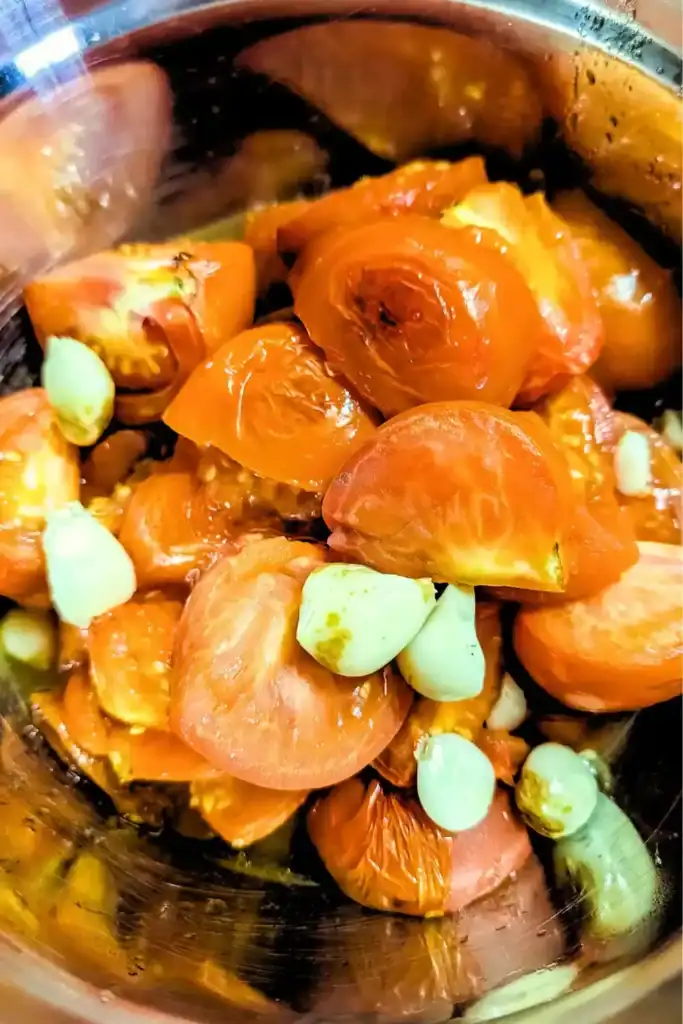 roasted tomatoes and garlic in stainless steel mixing bowl