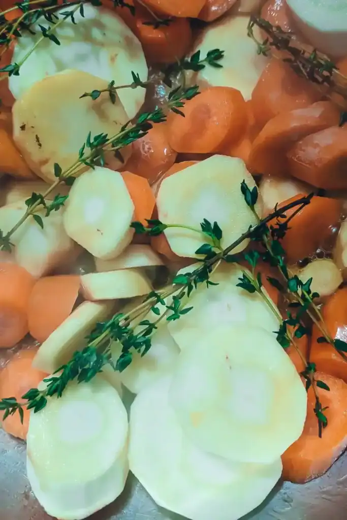 adding carrots and parsnips with sprigs of thyme to pan