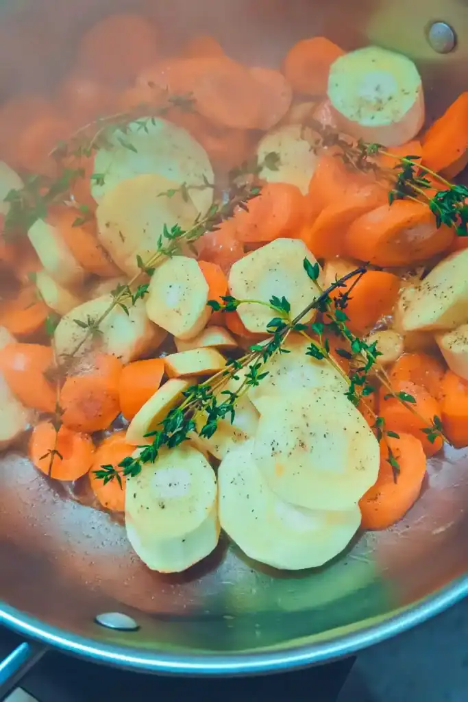 adding salt and pepper to root vegetables in pan