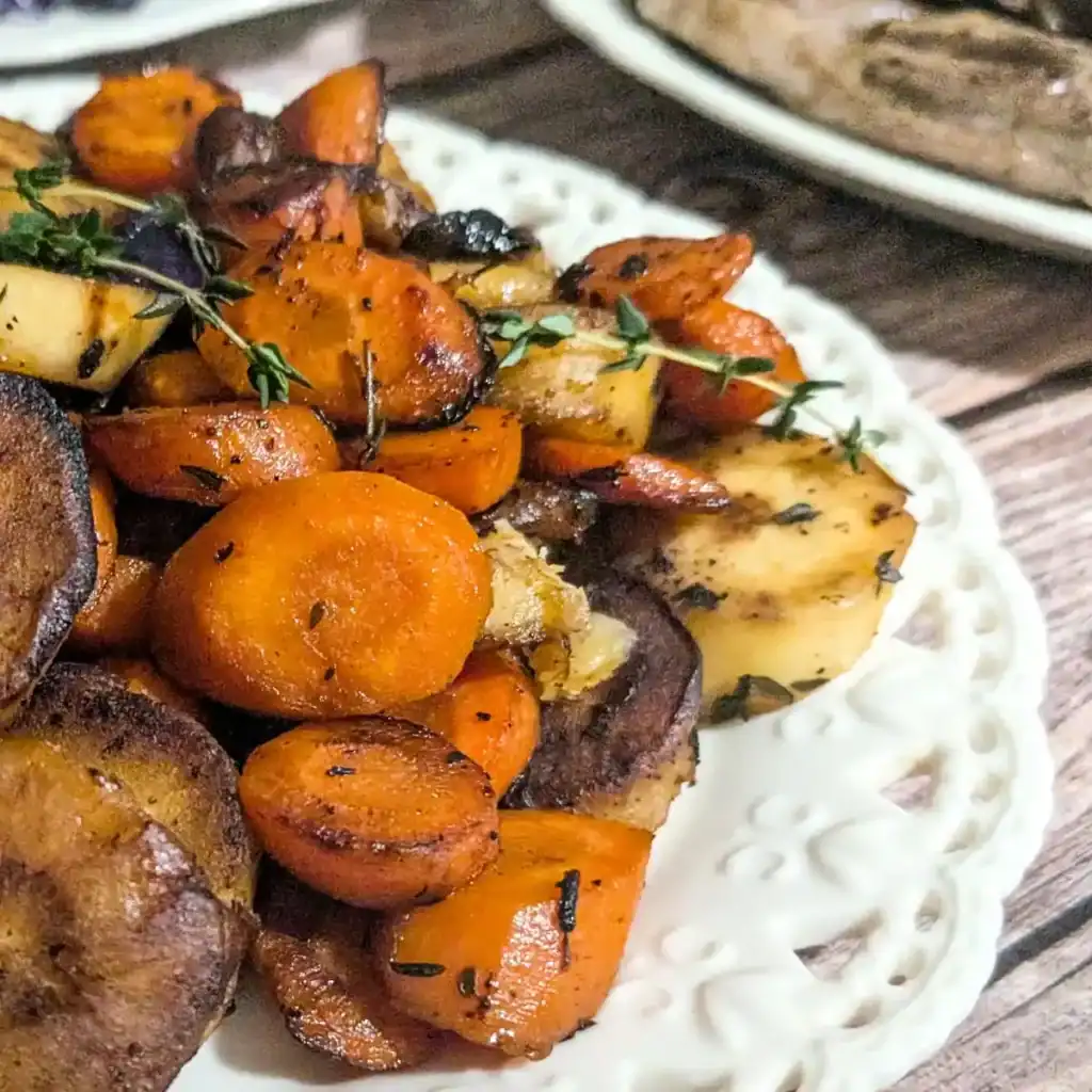 view of lace edged plate with sauteed carrots and parsnips on it with fresh thyme