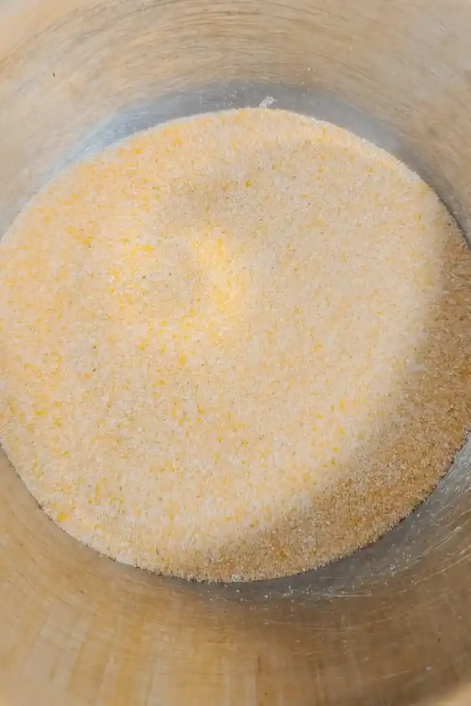 adding yellow cornmeal to mixing bowl