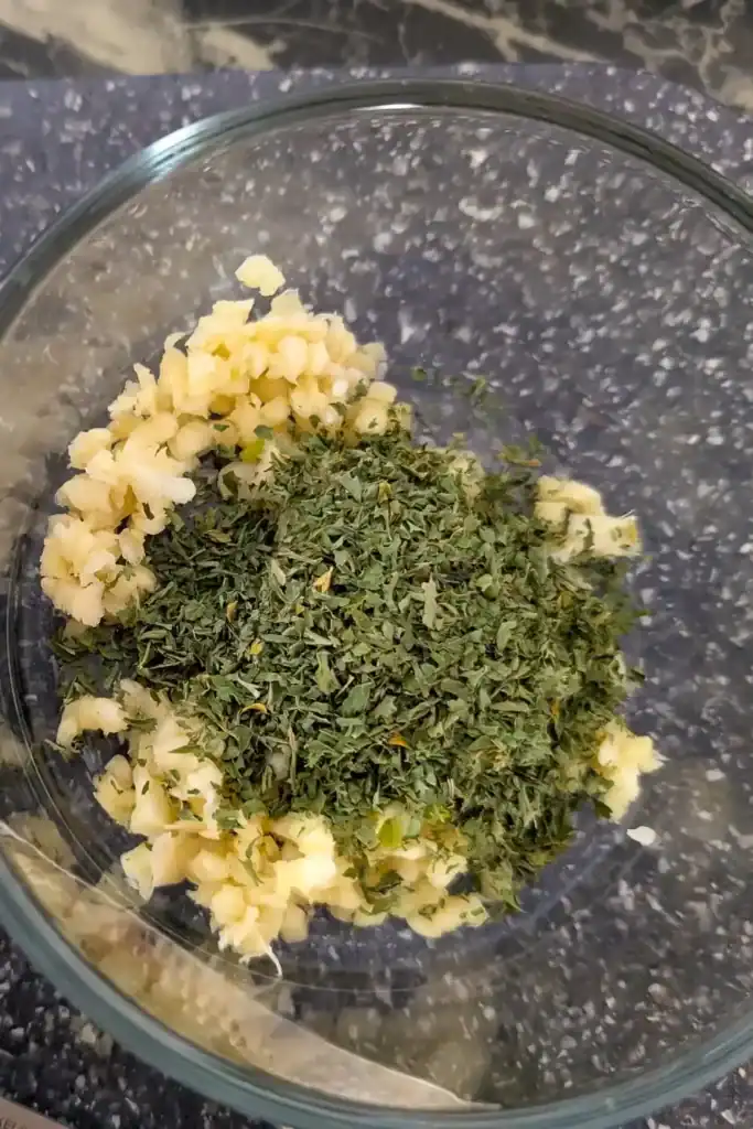 mince garlic and dry parsley in glass bowl