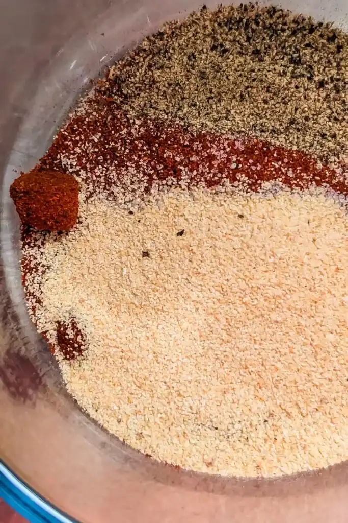 adding black pepper and garlic powder to spice blend for chicken