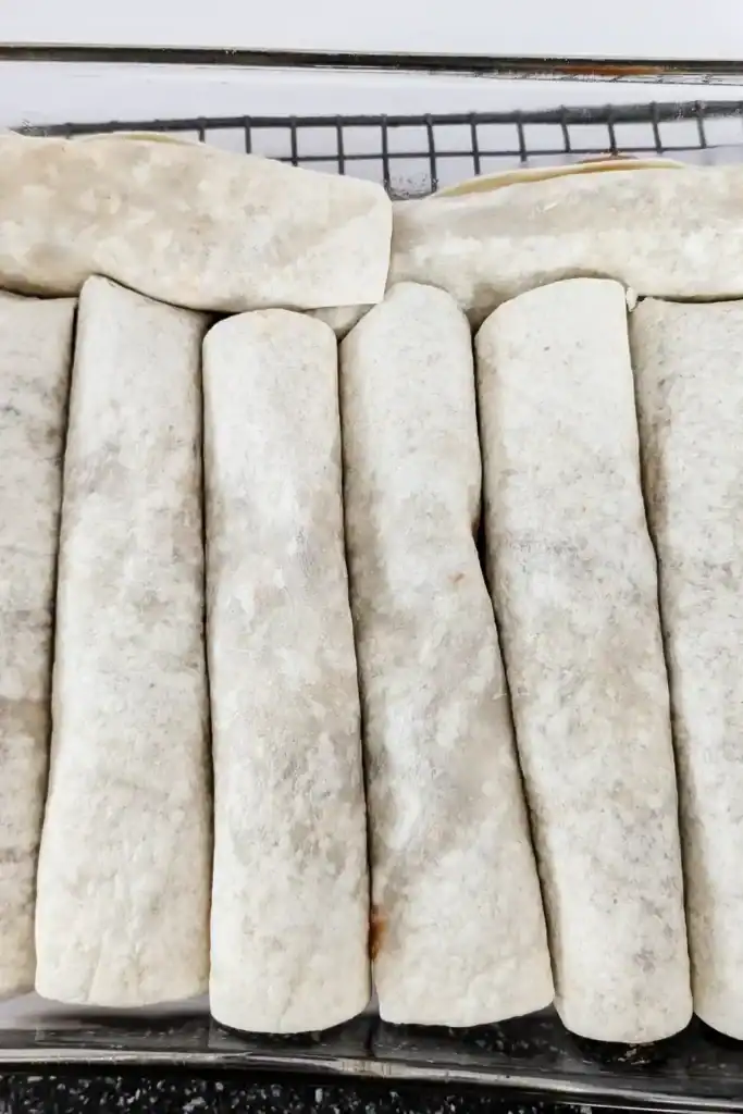 filling the baking pan with rolled enchiladas unbaked