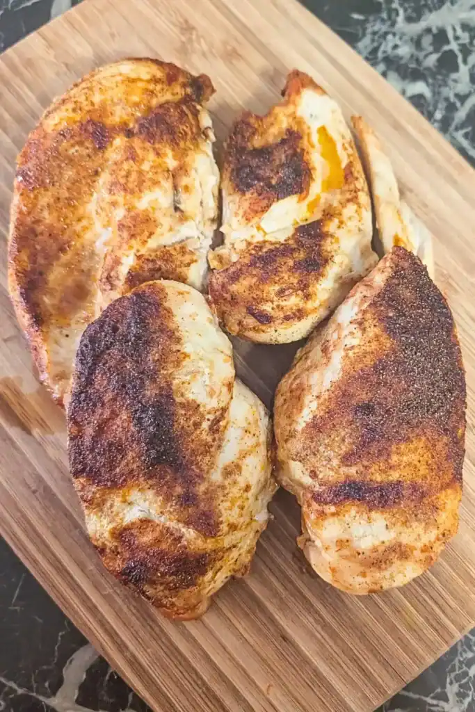 four spiced air fried chicken breast on cutting board