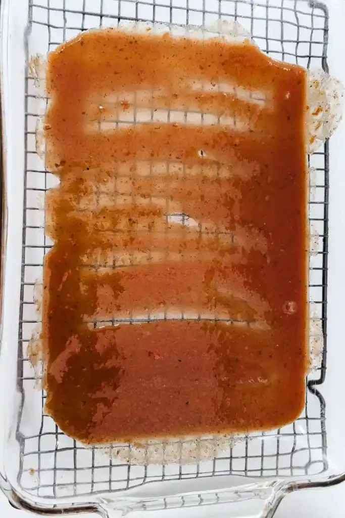 spreading the red enchiladas sauce in the bottom of glass 9x13 pan