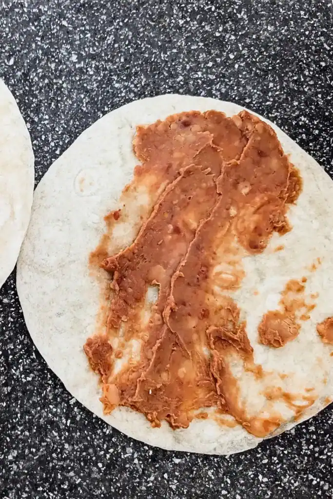 spreading the refried beans on flour tortilla