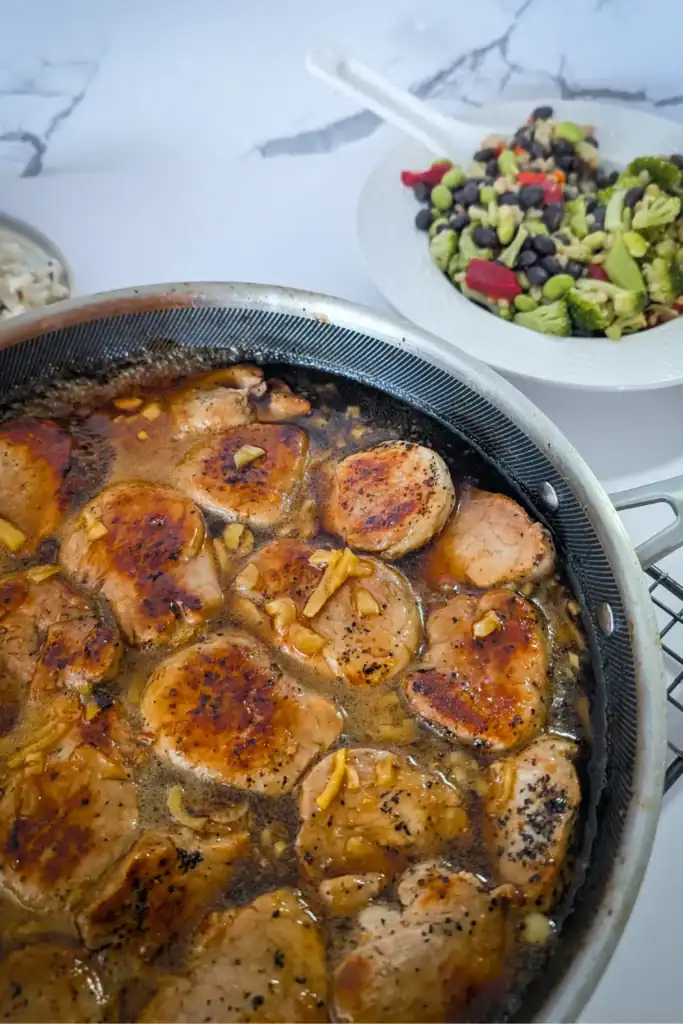 a angle of the pork tenderloin medallions with beans and broccoli in background