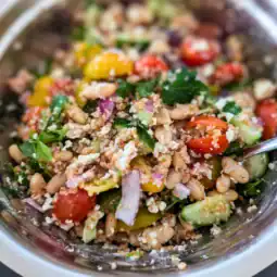 the salad all mixed together the edge of the stainless steel bowl around the salad