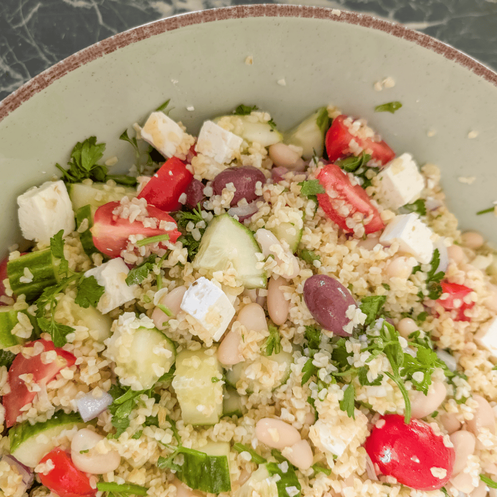Fresh Mediterranean bulgur and white bean salad with vegetables and herbs.