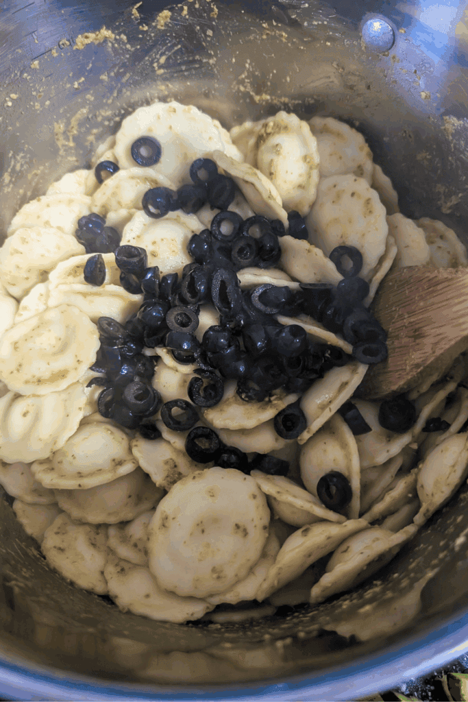 adding rip olives to pot with pasta