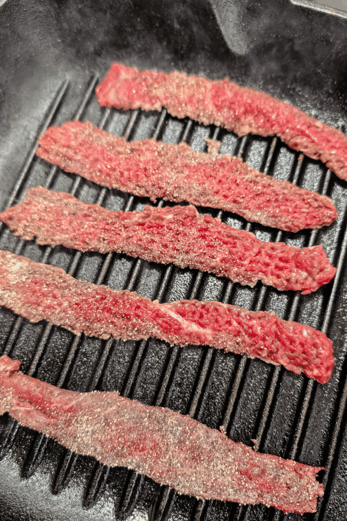 adding steak strips to hot grill pan