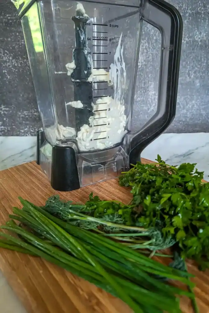 cottage cheese in blender-on wood cutting board with green herbs