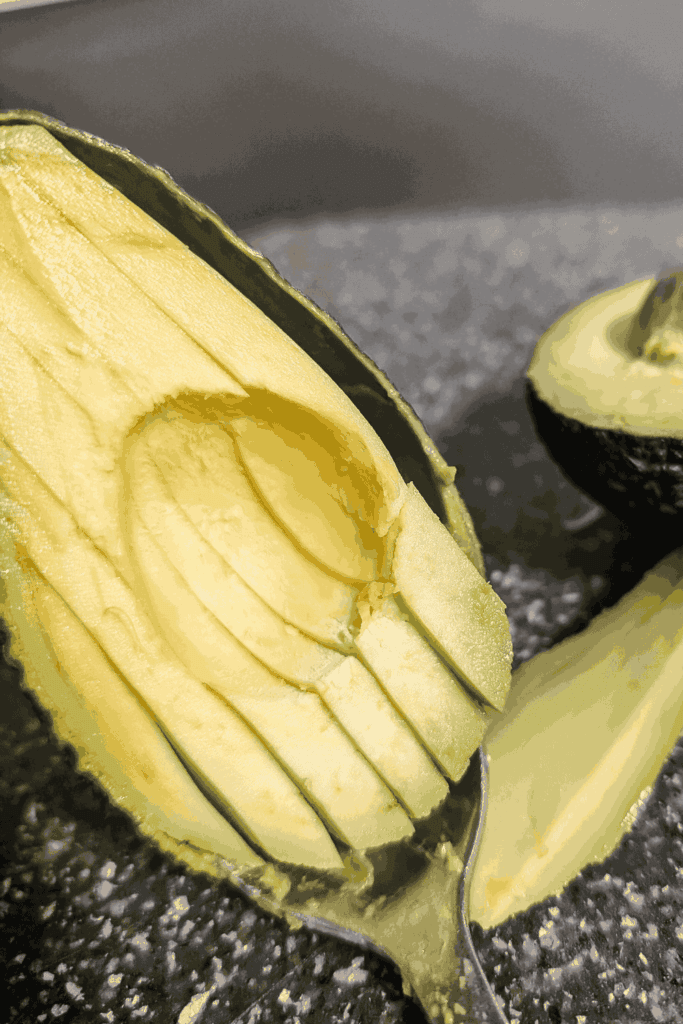 showing how to insert the spoon to remove avocado from peel