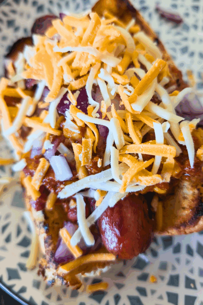 adding onions and cheese to the hot dog