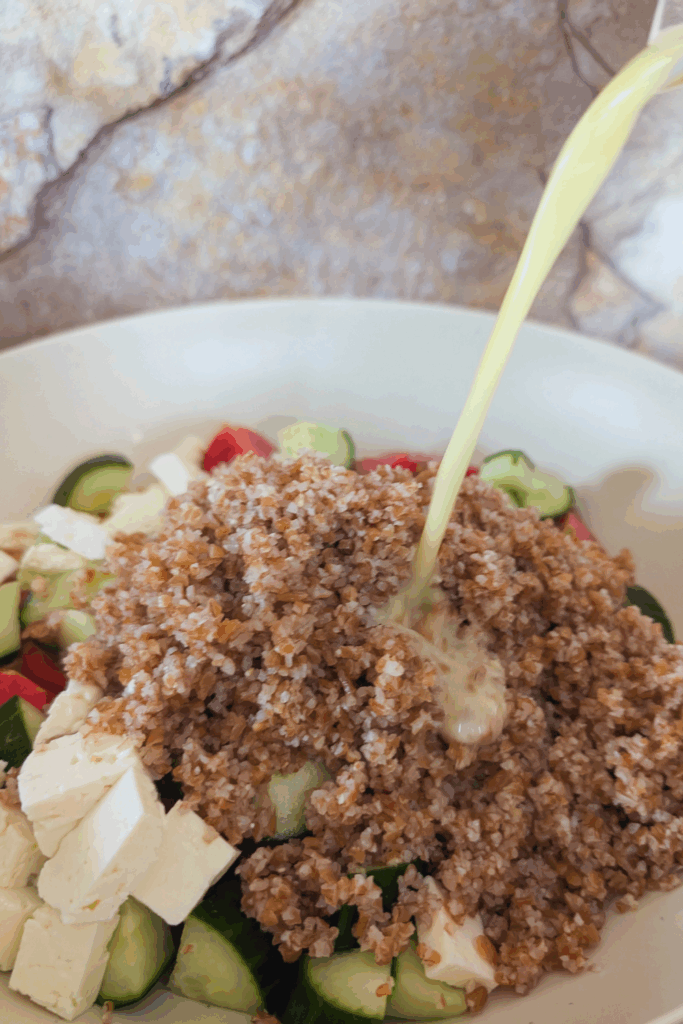 adding the lemon dijon vinaigrette to salad