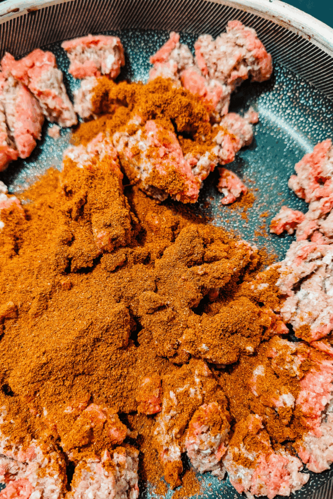adding the spices to the ground beef as it cooks