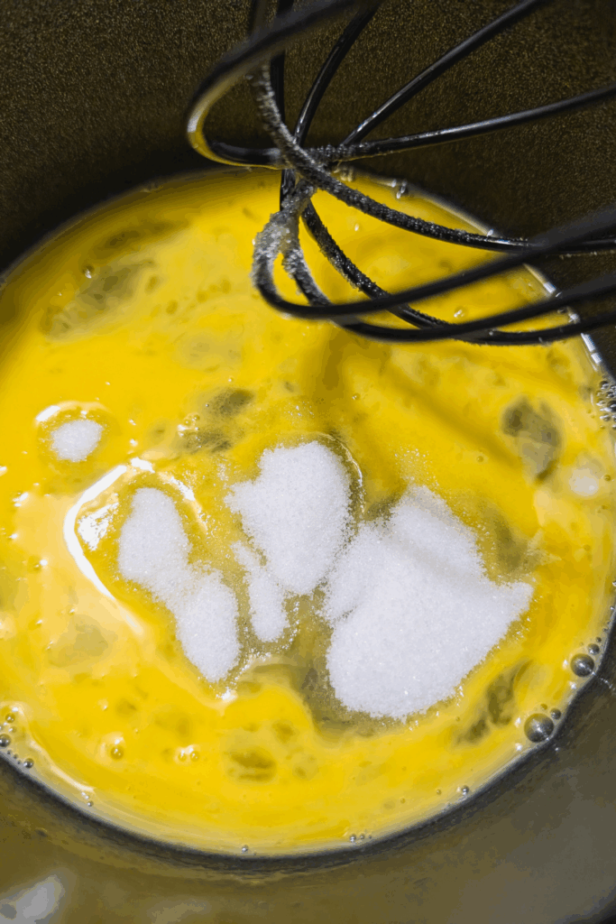 adding white sugar to eggs for dressing