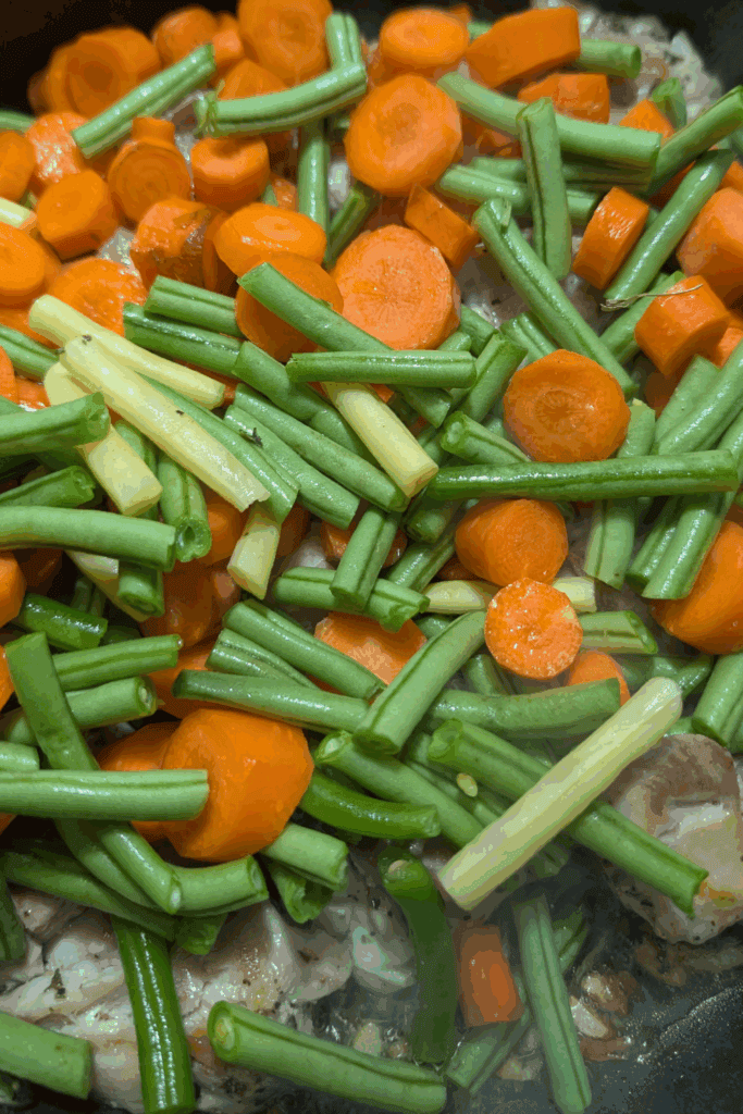adding carrots and bean to pan with chicken
