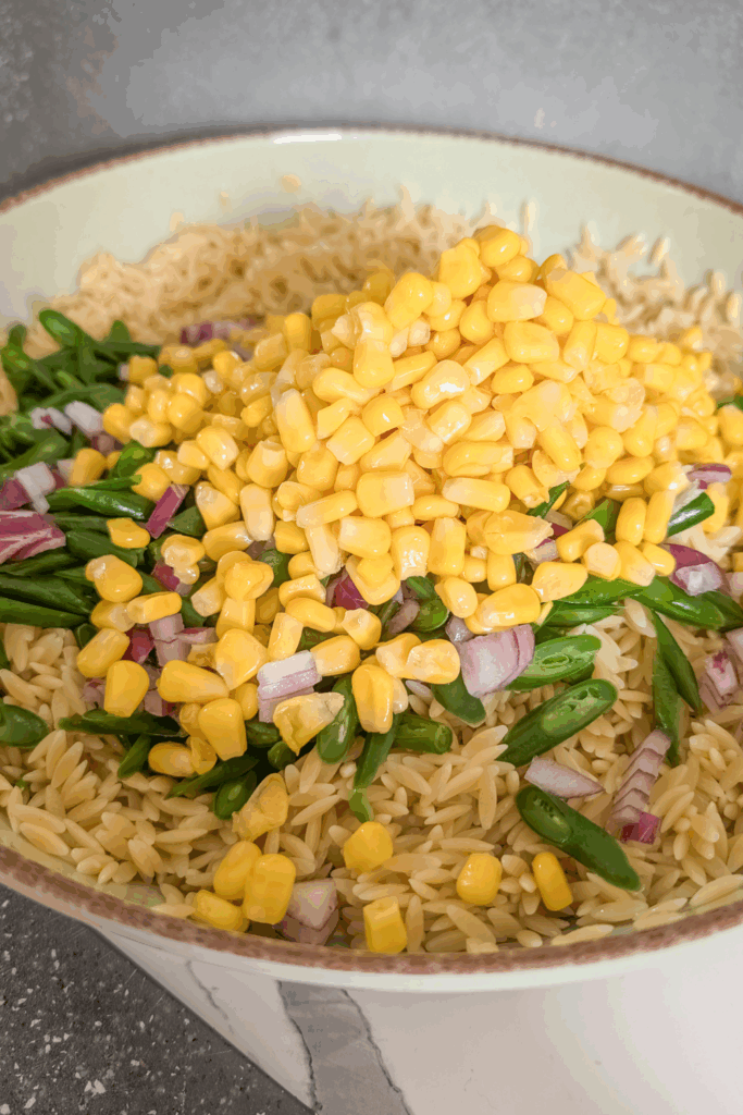 adding corn and onion to salad bowl