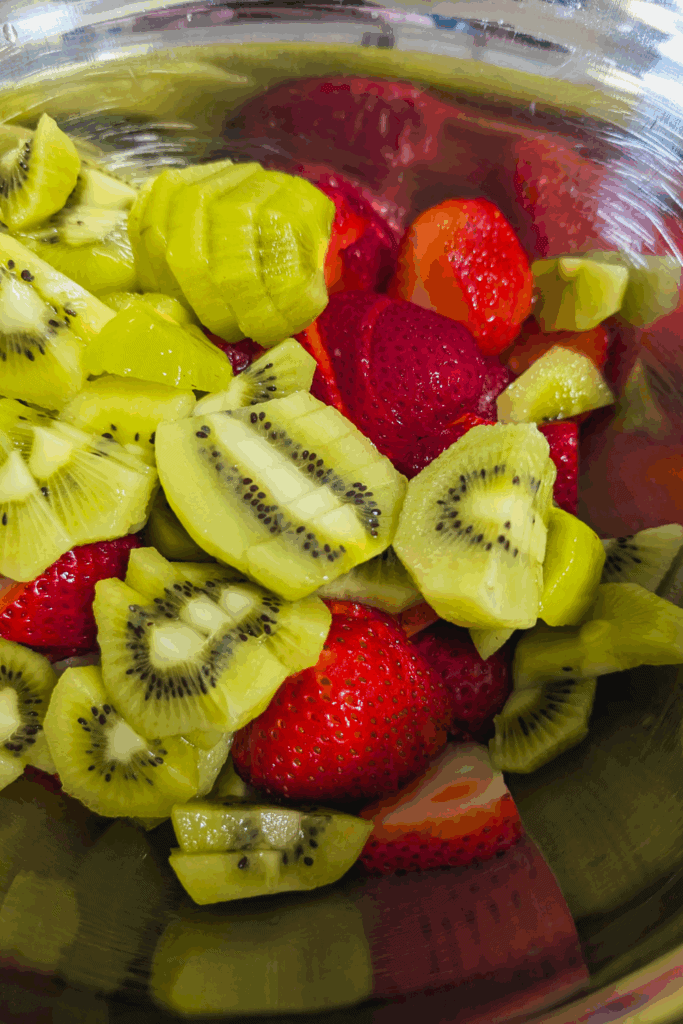 Fresh sliced kiwi and strawberries in a metal bowl, vibrant and healthy fruit for smoothies or snacks.