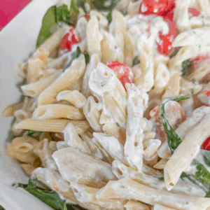 Creamy pasta salad with cherry tomatoes and fresh herbs, perfect for summer gatherings and easy weeknight dinners.
