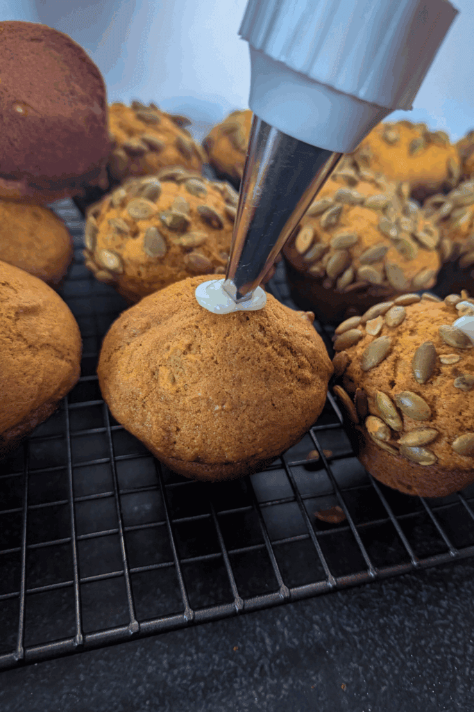 Buttercream piping on freshly baked cookies with sunflower seeds on top.
