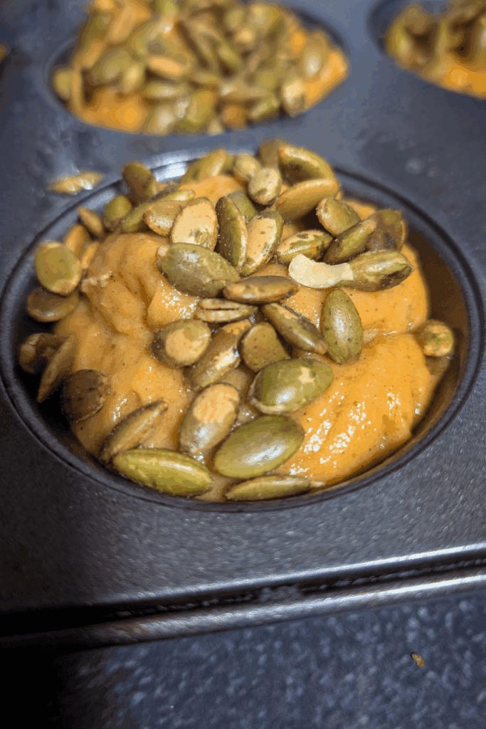 Roasted pumpkin seeds on a baking sheet with pumpkin spice mixture, healthy snack.