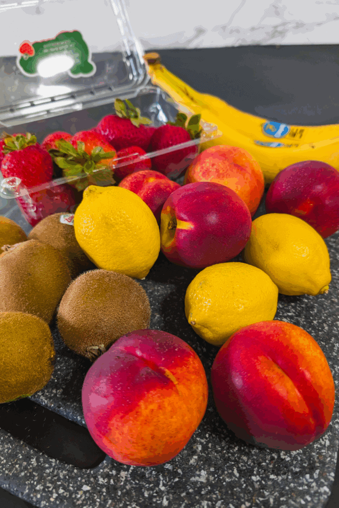 Fresh assorted fruits including strawberries, lemons, peaches, kiwis, and bananas for healthy cooking and recipes.