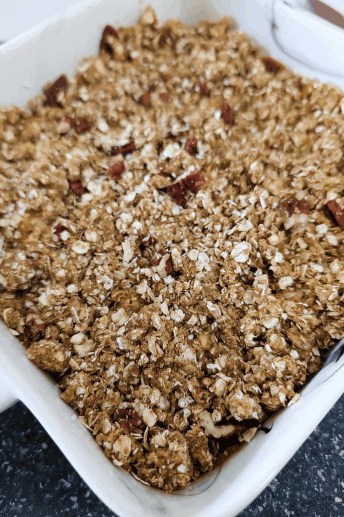 Oatmeal crumble topping in a white baking dish, ready for baking.