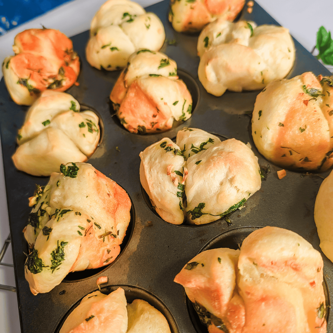 Fluffy herb-infused cheese muffins baked in a muffin tin for flavorful snack or breakfast options.