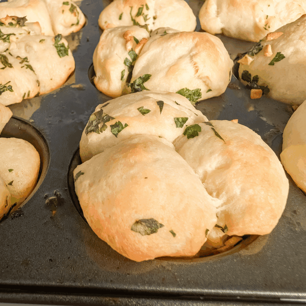 Fluffy garlic herb bread rolls fresh out of the oven on a baking sheet.