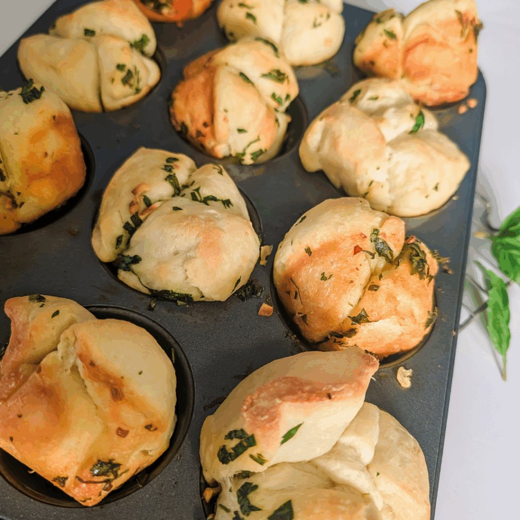 Freshly baked garlic herb muffins in a mini muffin pan, perfect for snacks or breakfast.