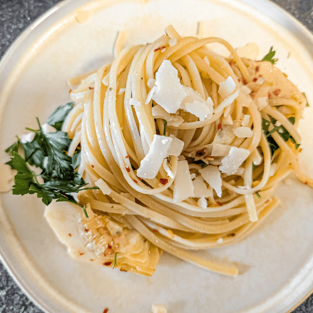 Creamy Parmesan pasta with shaved cheese and fresh herbs on a rustic plate.