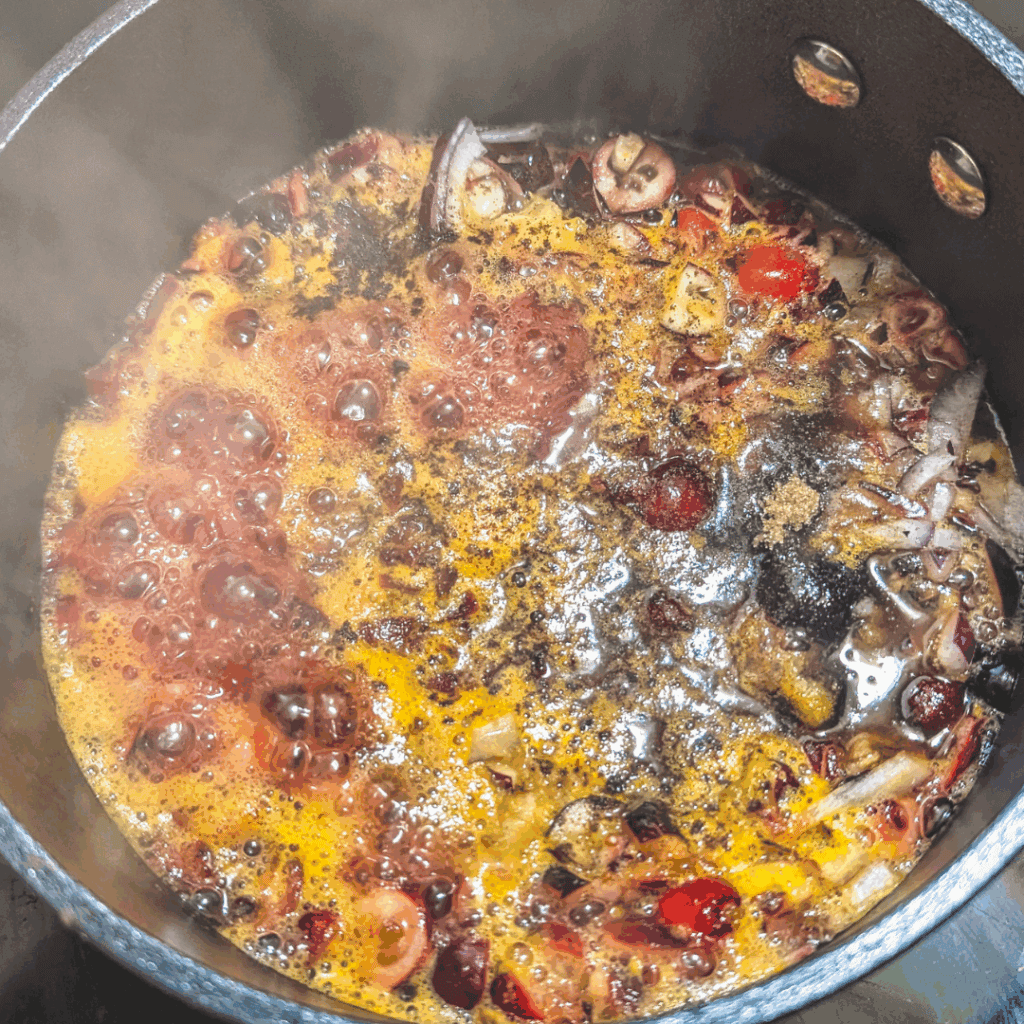 Boiling chopped onions and tomatoes in a pot for cooking, with steam rising from the mixture.