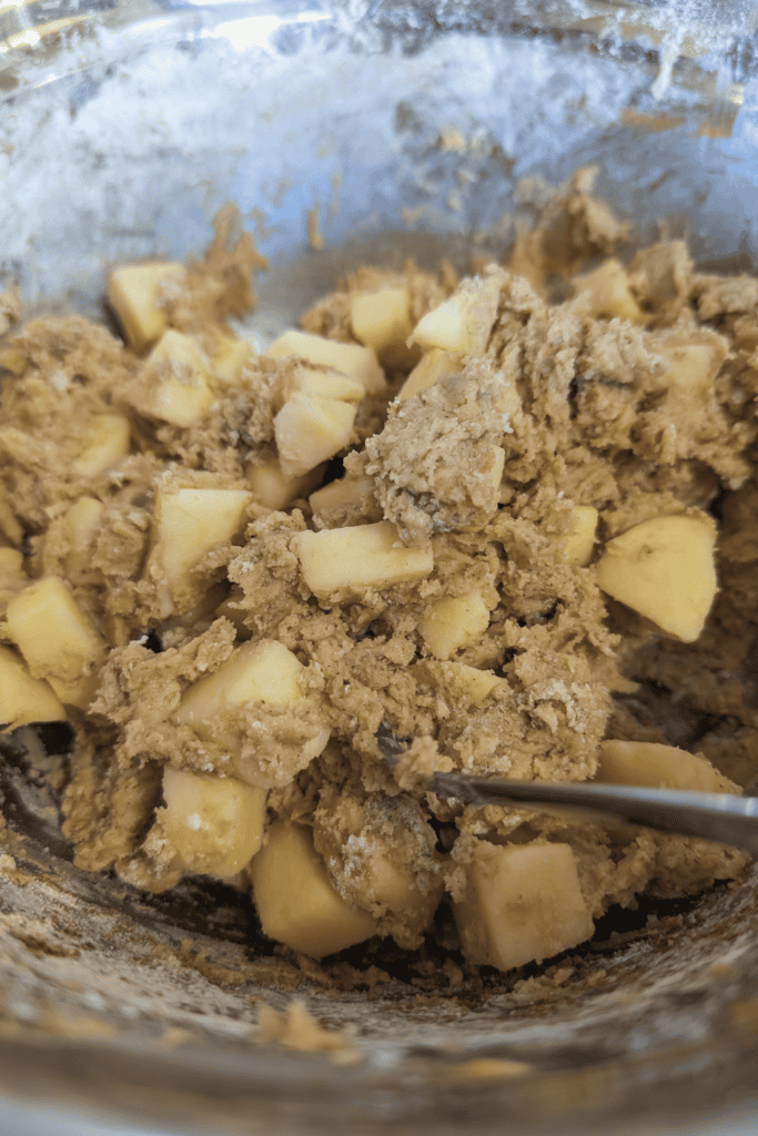 Cookie dough with chunks of white chocolate in a mixing bowl.