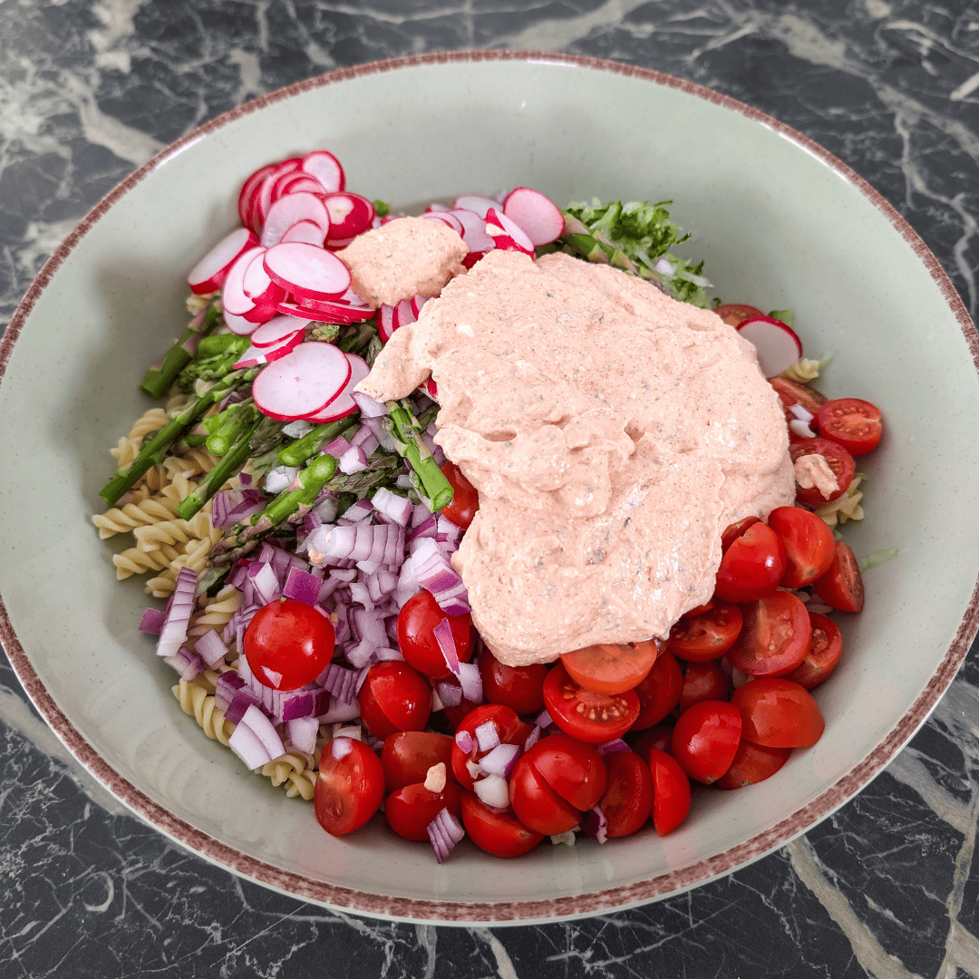 Cottage cheese salad dressing with fresh vegetables and pasta in a bowl.