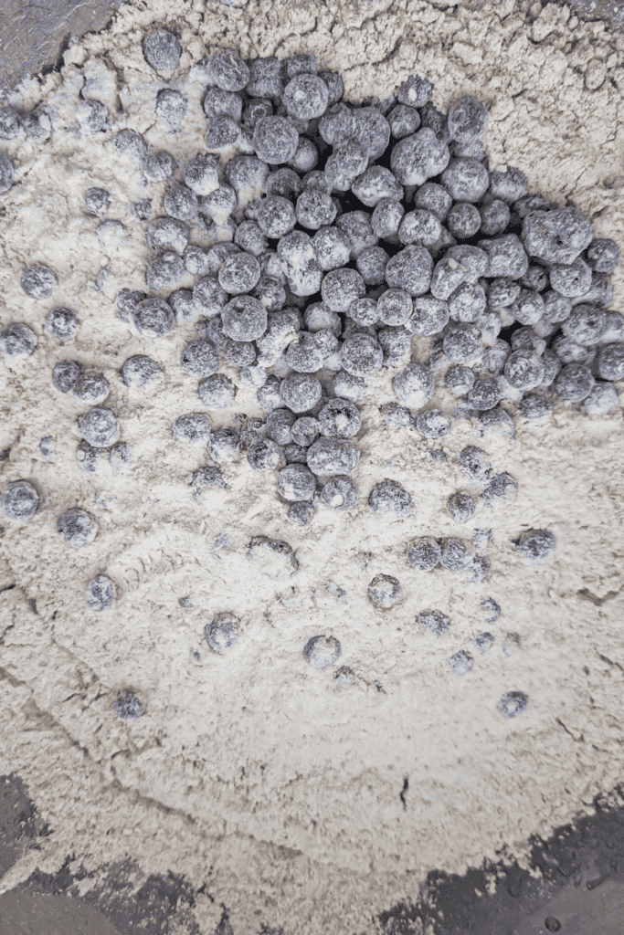 Frozen Canadian wild blueberries scattered on sandy surface for baking.
