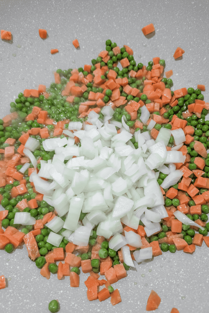 Chopped onions, carrots, and peas for shrimp fried rice recipe.