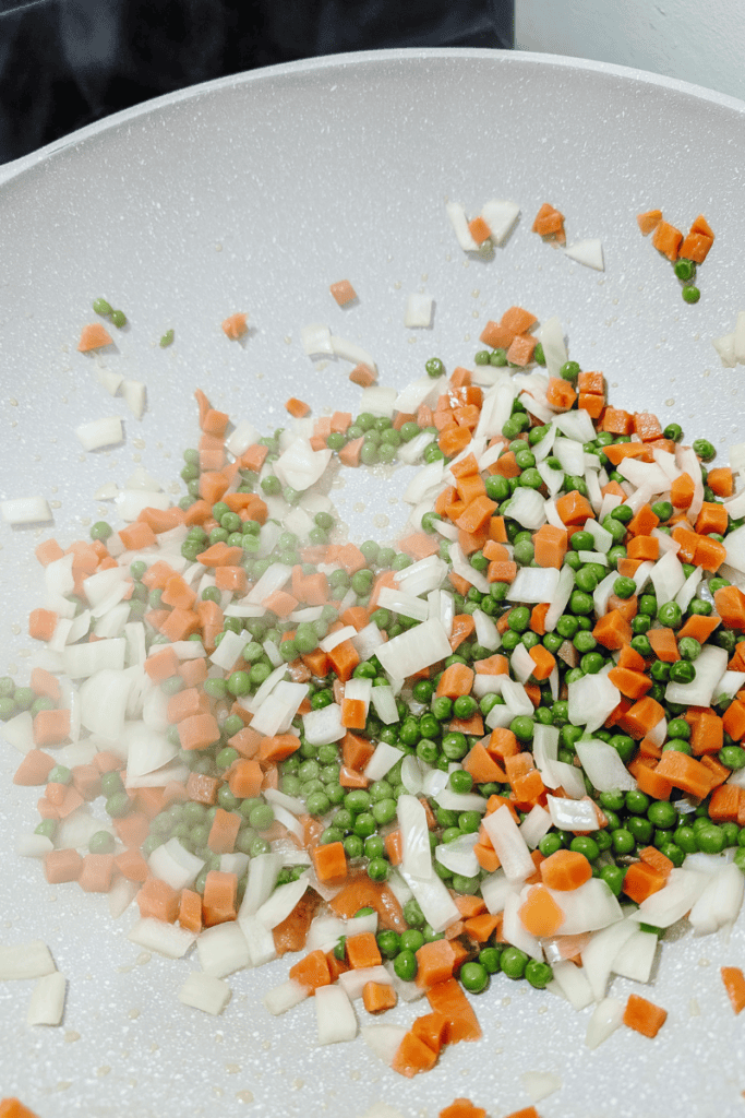 Stir-fried shrimp, rice, eggs, carrots, and peas in a wok for easy weeknight dinner.