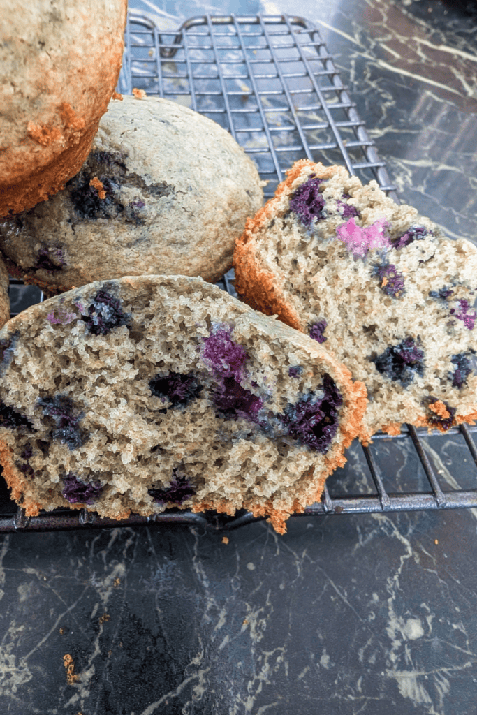 Freshly baked blueberry muffins with frozen Canadian wild blueberries on a cooling rack.