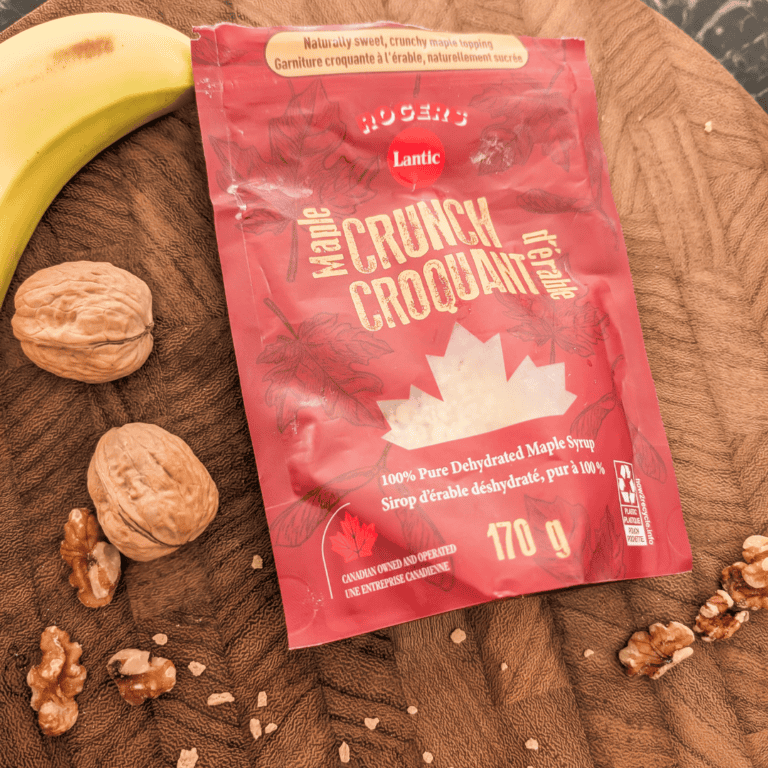 Maple Crunch syrup packet on wooden surface with walnuts and banana.